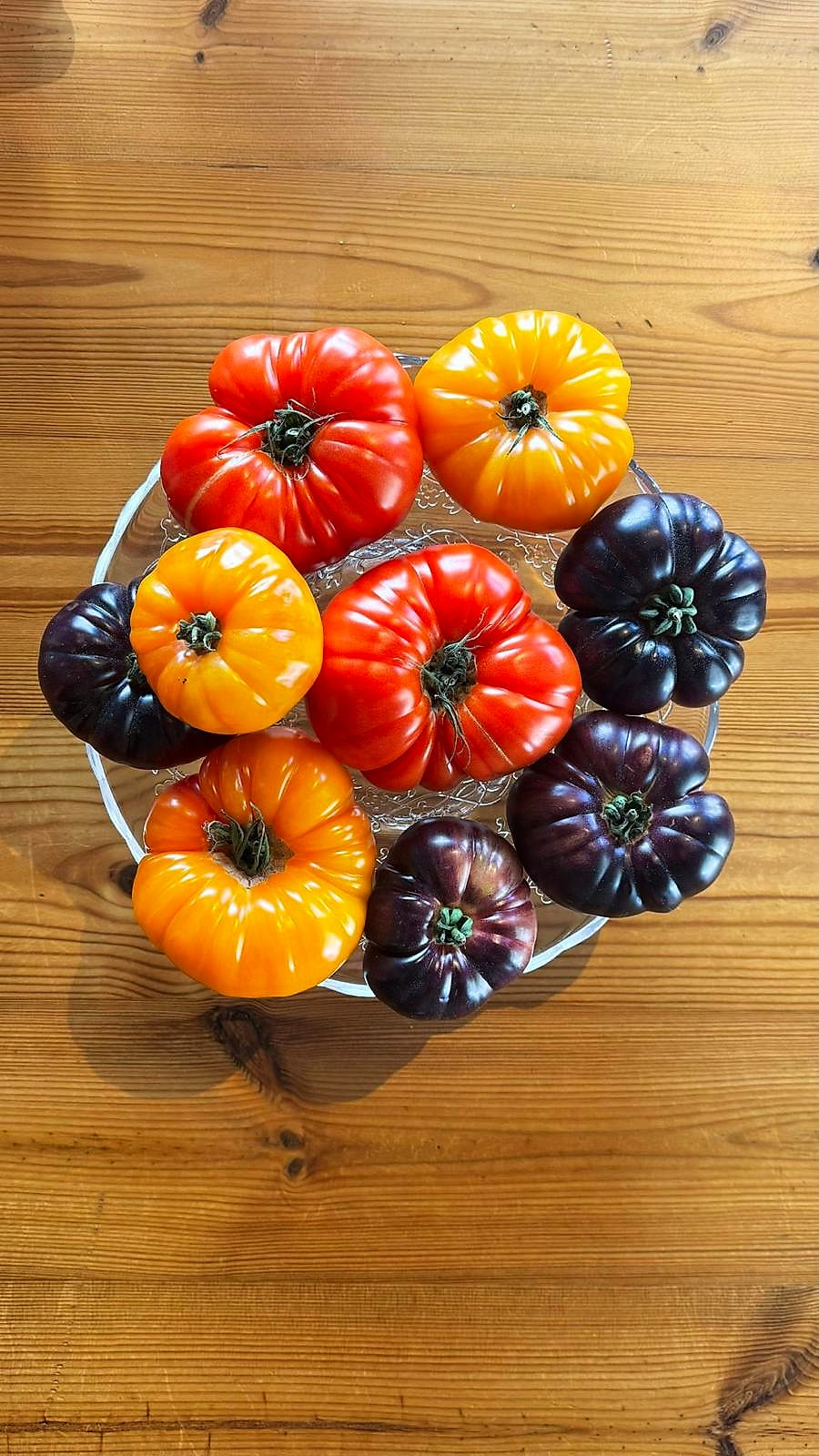 Red, yellow and purple heirloom tomatoes on a glass plate